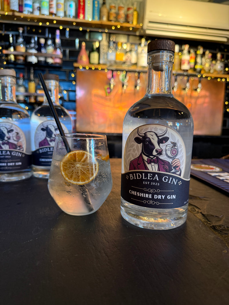 Biddlea Gin bottle with a glass of gin and tonic on a bar counter.