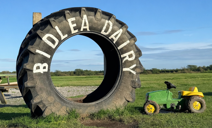 Large tyre with 'Biddlea Dairy' branding in a field with a tractor.